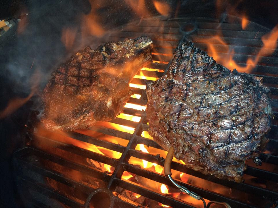 a couple of steaks on a charcoal grill